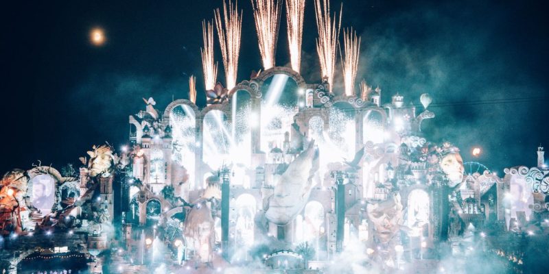 Festival EDM malam hari dengan panggung dan sorotan lampu spektakuler