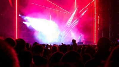 Kerumunan penonton menyaksikan panggung festival dengan lampu terang