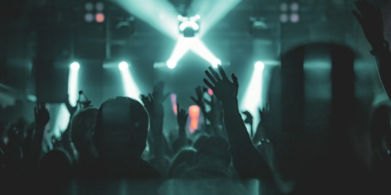 Penonton mengangkat tangan di bawah lampu panggung konser
